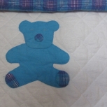 Blue teddy is sleeping on the quilt